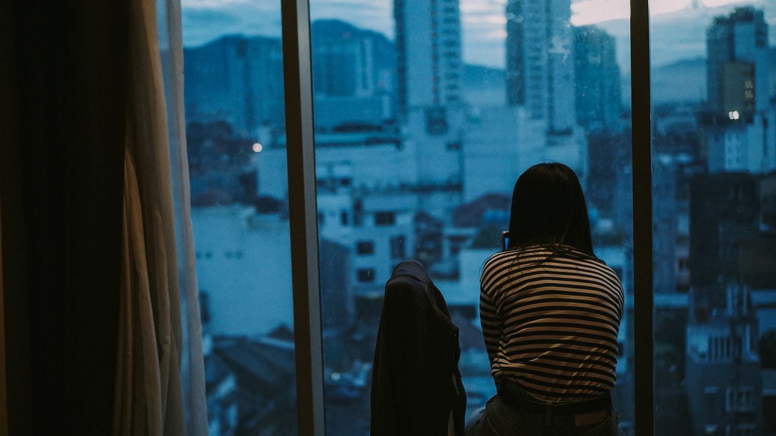 woman in black and white striped long sleeve shirt standing near glass window